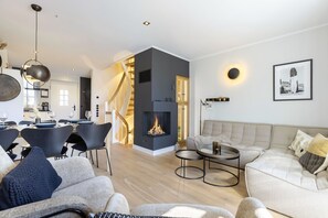 Una sala de estar moderna con chimenea, un comedor y una escalera que conduce a un nivel superior.