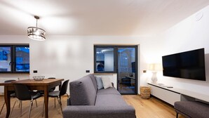 En moderne stue med en grå sofa, et træspisebord og et fladskærms-tv på væggen.