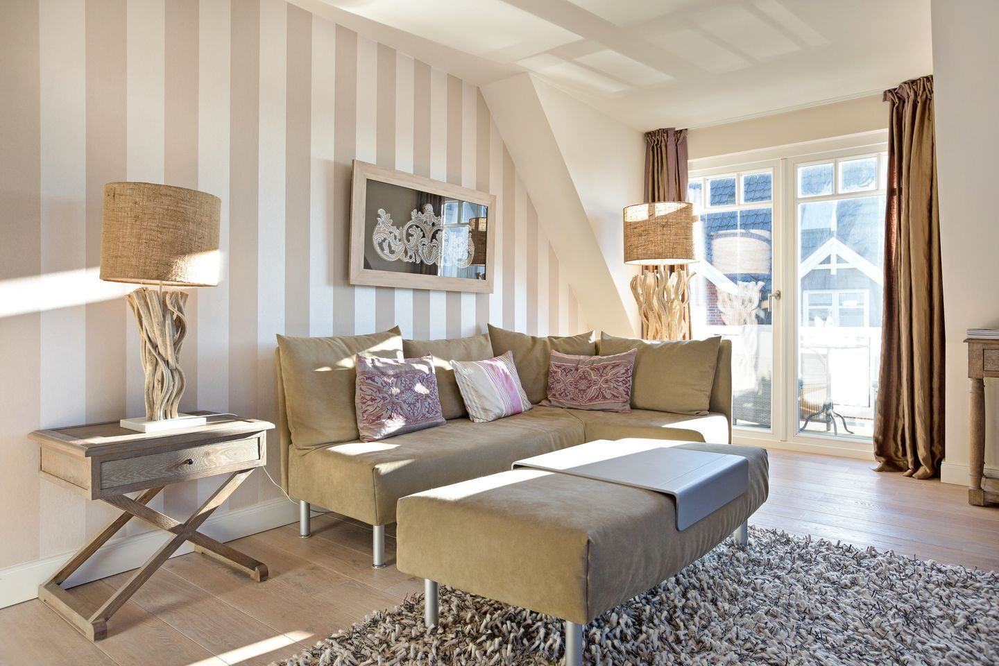 Un salon avec un mur à rayures, un canapé, une table basse et une lampe.