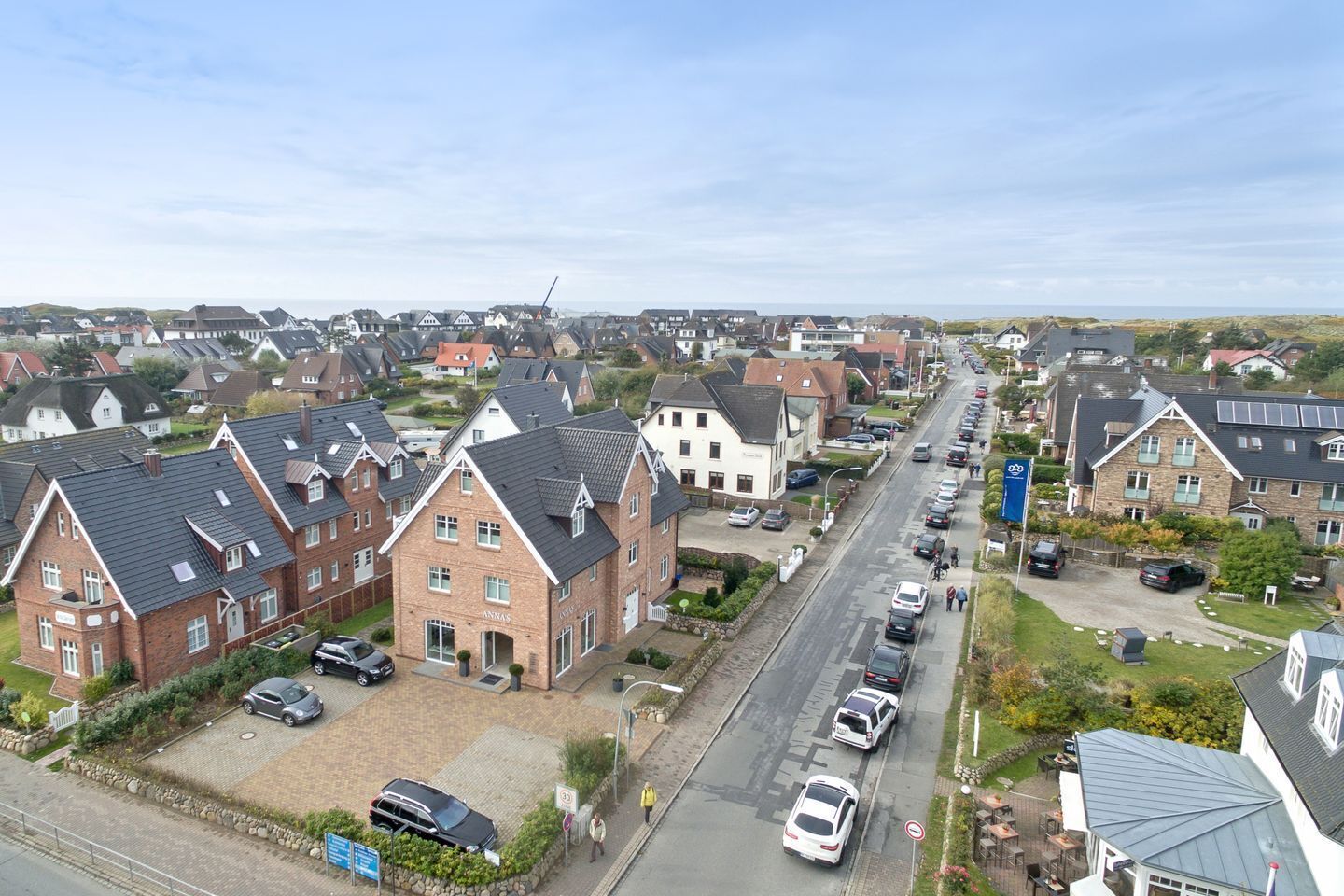 Una calle residencial con casas, coches y cielo despejado.