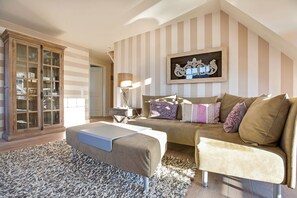 A cozy living room with a sofa, ottoman, and a cabinet with glass doors. - Maisonette No. 8 - Erleben Sie Einen der Beliebtesten Urlaubsorte der Insel Sylt - Wenningstedt (Wenningstedt-Braderup (Sylt))