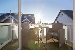 A balcony with wicker furniture, a table, and a bottle of water. - Maisonette No. 8 - Erleben Sie Einen der Beliebtesten Urlaubsorte der Insel Sylt - Wenningstedt (Wenningstedt-Braderup (Sylt))