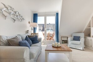 Un salon moderne avec un canapé, un fauteuil et une table décorée de bougies.