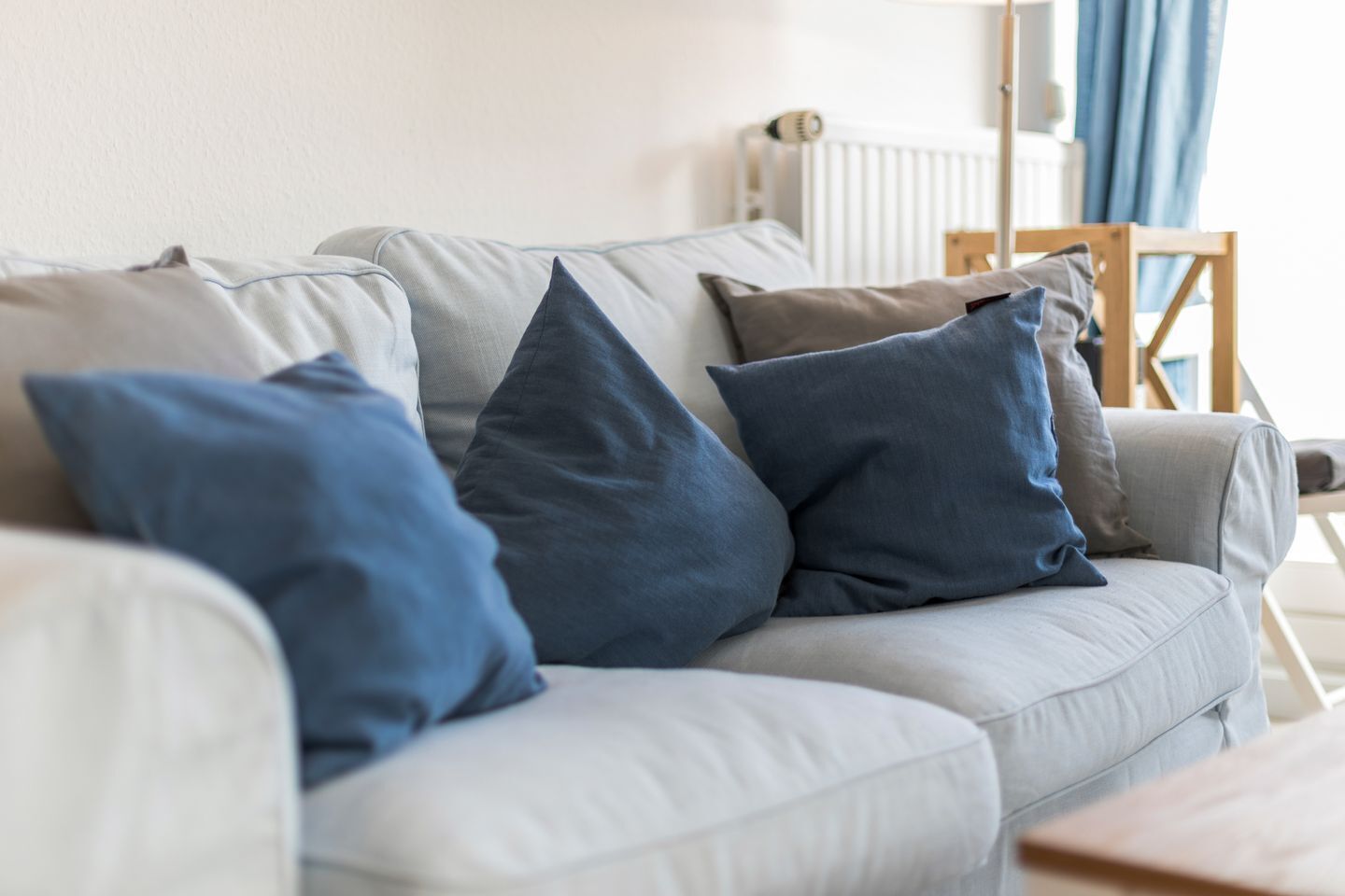 A light grey sofa with multiple cushions in shades of blue and grey.