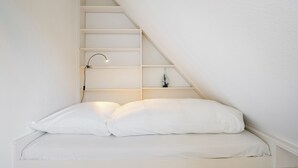 Eine weiße, geneigte Decke mit integriertem Regal und einer Schreibtischlampe.