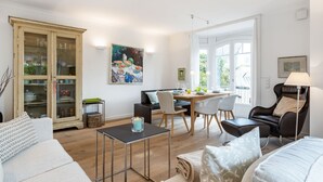 Un salon moderne comprenant un coin repas, un canapé, une table basse et un meuble avec des portes en verre.