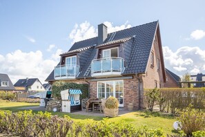 Une maison à deux étages avec un balcon, un jardin et un vélo.