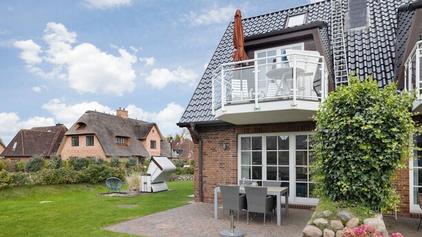 Ein Haus mit Balkon, Garten und Satellitenschüssel.