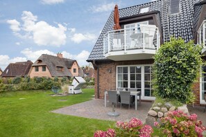 Een huis met een balkon, een tuin en een schotelantenne.