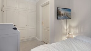 Ein Schlafzimmer mit einem Bett, einem Schminktisch, einem Kleiderschrank, einem Gemälde und einer Lampe.