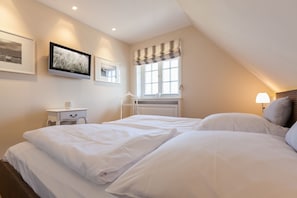 Une chambre avec deux lits, une table de chevet, une lampe et une fenêtre avec des rideaux.