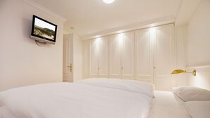 A bedroom with a large bed, a television mounted on the wall, and a wardrobe with multiple doors. - Heide & Meer, App. 4 - Sylt. Heide. Und Meer (Wenningstedt-Braderup (Sylt))
