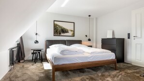 Ein Schlafzimmer mit Bett, Schreibtisch, Stuhl, Kleiderschrank und einem Bild an der Wand.