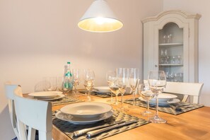 A dining table set with plates, glasses, and cutlery, a bottle, and a lamp.