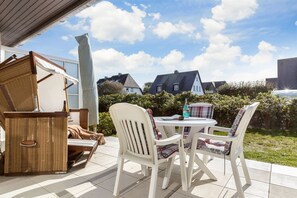 An outdoor patio with wicker furniture and a table with a bottle and menu. - Haus Carina, App. 55 - 3-raum Appartement im Erdgeschoss und Untergeschoss mit ca. 65m² (Wenningstedt-Braderup (Sylt))