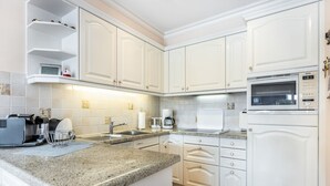 Une cuisine moderne avec des meubles blancs, un plan de travail en granit, un four à micro-ondes de la marque Bosch et une machine à café.