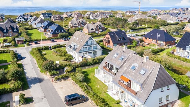 Un quartier résidentiel avec des maisons, une route et une étendue d’eau en arrière-plan.