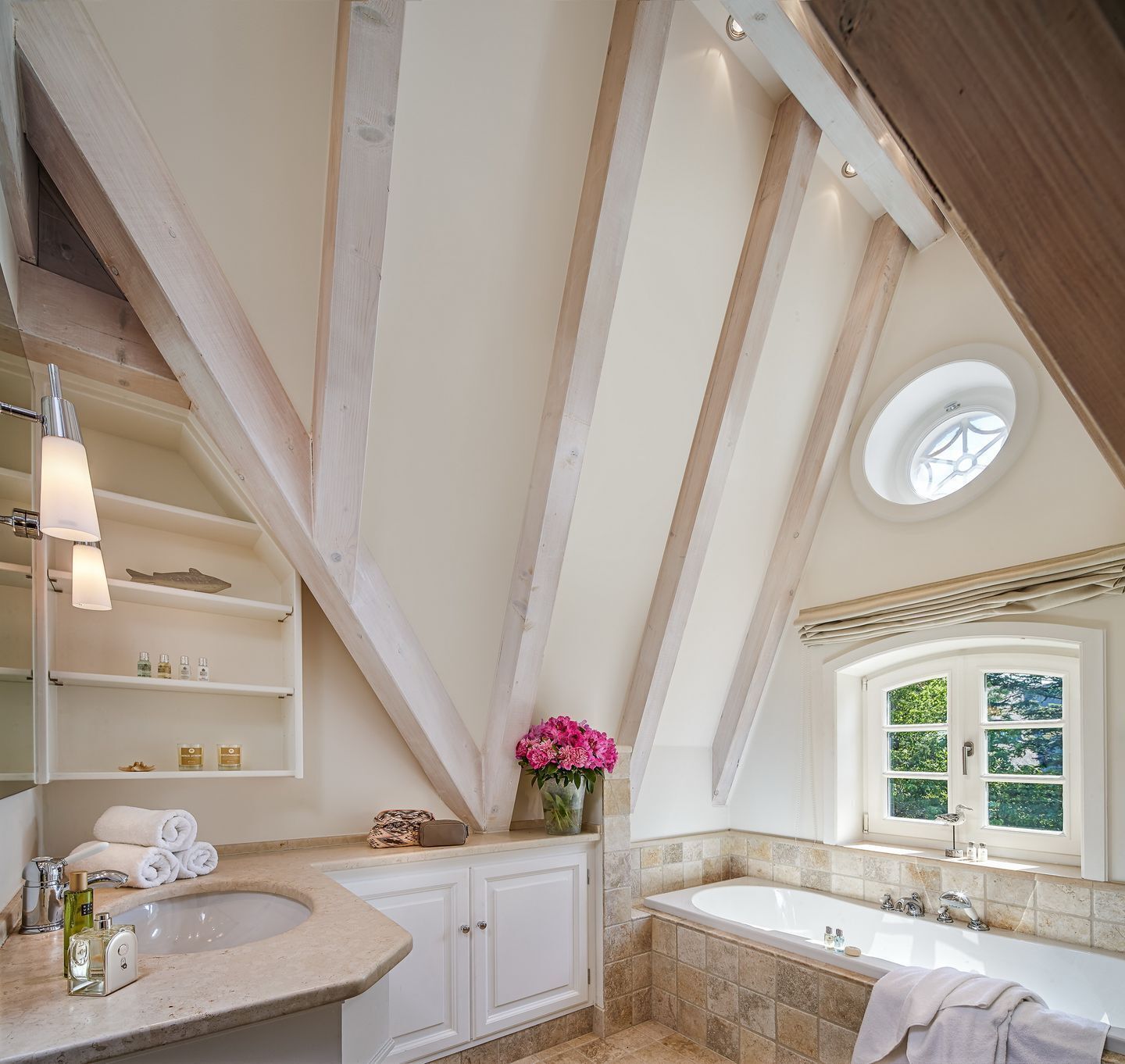 Une salle de bain avec une baignoire sur pieds, une grande fenêtre et un puits de lumière.