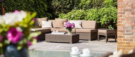 An outdoor seating area with a sofa, a coffee table, and a chair.