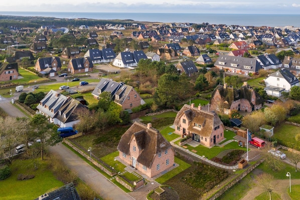 An aerial view of a residential area with houses, roads, and a body of water in the background.