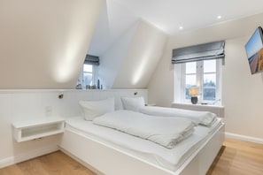 A bedroom with a loft bed, a window with a view, and a bedside table with a lamp.