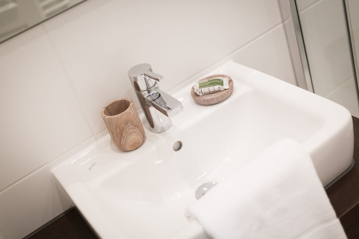 A bathroom sink with a wooden cup holder, a soap dish, and a towel.
