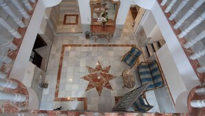 A grand lobby with a star-shaped floor centerpiece, marble flooring, and a large mirror above a console table.