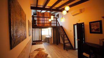 A room with a bed, a desk, a chair, a staircase, and a bathroom.