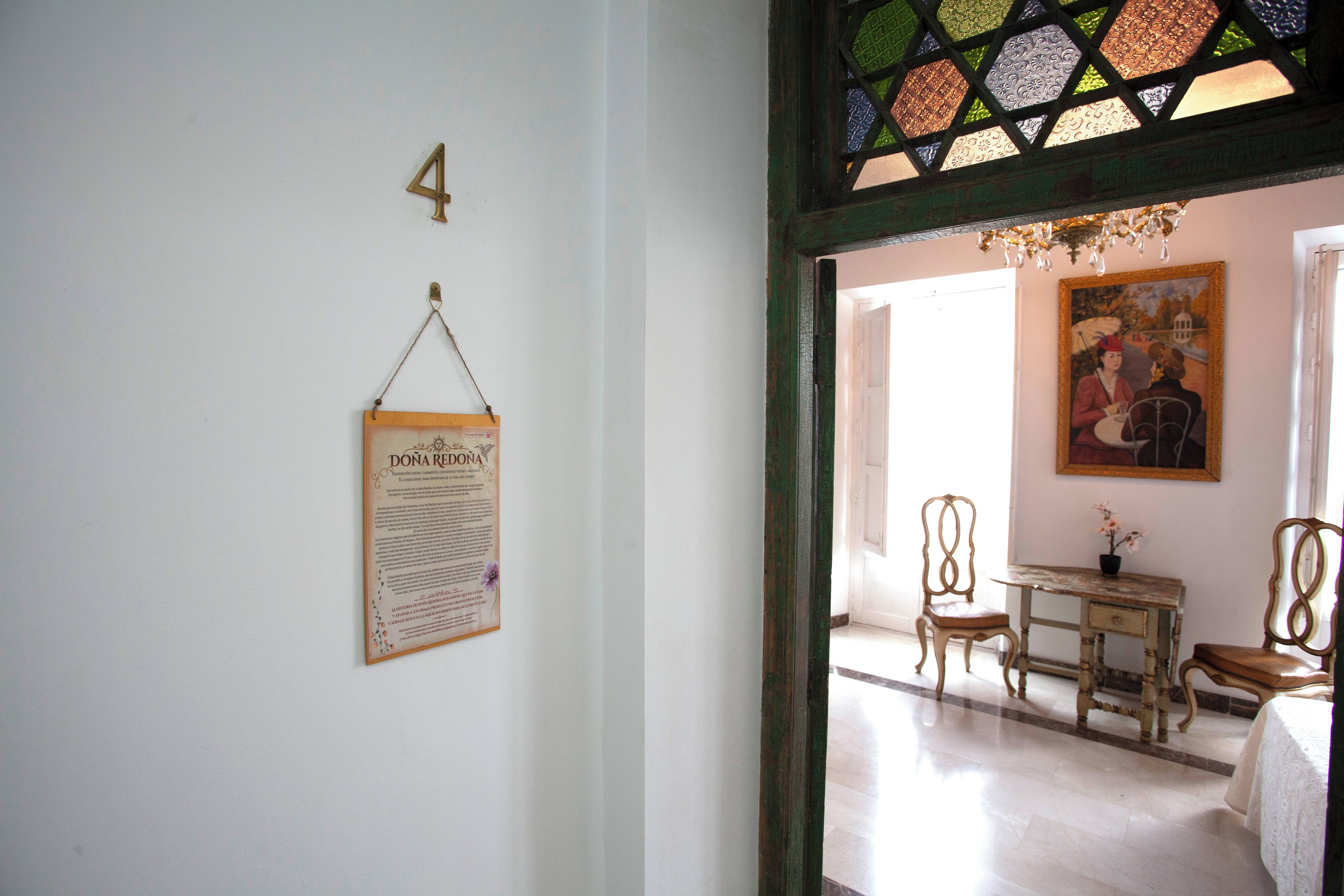 Una habitación con un escritorio de madera, dos sillas, un cuadro en la pared y un cartel con el número 4.