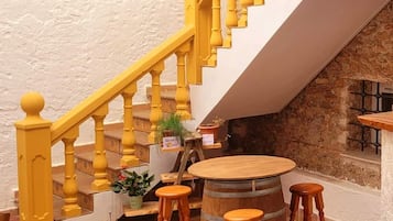A staircase with yellow balusters, a round wooden barrel, and three wooden stools.