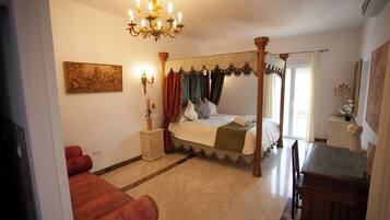 A bedroom with a four-poster bed, a chandelier, a dresser, and a desk.