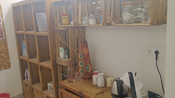 A kitchen with wooden cabinets, a coffee maker, and a shelf with jars and a vase.