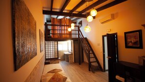 A room with a bed, a desk, a chair, a staircase, and a bathroom.