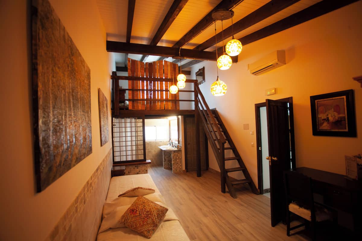 Ein Zimmer mit einem Bett, einem Schreibtisch, einem Stuhl, einer Treppe und einem Badezimmer.