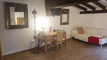 A room with a wooden dining table, two chairs, a white sofa, and a mirror on the wall.