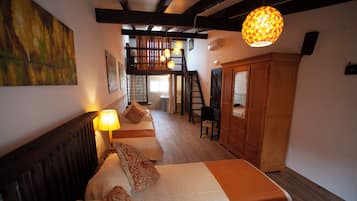 A bedroom with two beds, a wooden wardrobe, a staircase, and a hanging light fixture.