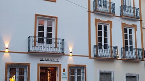A building with multiple balconies, a central entrance, and a courtyard with a fountain.
