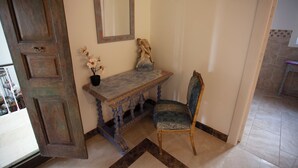 Une pièce avec une porte en bois, un banc, une chaise, un miroir et une petite table sur laquelle est posée une plante en pot.