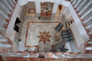 Un lobby imponente con un centro de piso en forma de estrella, pisos de mármol y un espejo grande sobre una consola.