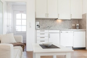 A modern kitchen with white cabinets, a coffee maker, and a dishwasher. - Haus Heideresidenz App. 24 - Willkommen in der Heideresidenz auf Sylt! (Wenningstedt-Braderup (Sylt))