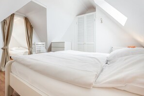 Ein Schlafzimmer mit einem Bett, einem Nachttisch, einem Sessel und einem Kleiderschrank.