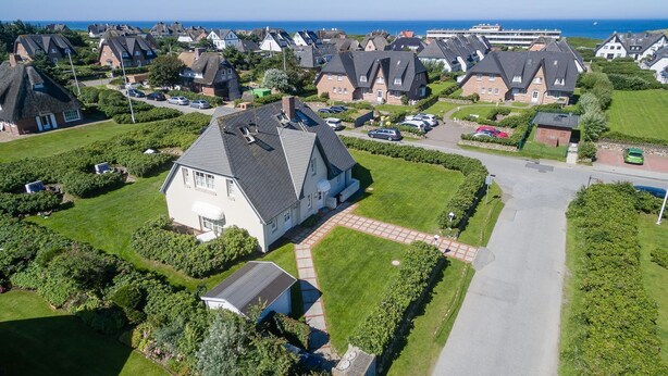 An aerial view of a residential area with houses, a well-maintained lawn, and a clear view of the sea. - Haus Heideresidenz App. 23 - Helles und Mordernes Zwei-raum-appartement (Wenningstedt-Braderup (Sylt))