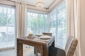 A dining area with a wooden table set for two, a candle, and wicker chairs. - Mer-du-nord - Mer-du-nord - Wunderschöne Wohnung im Riviera-landhausstil (Sylt)