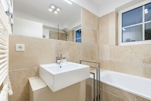 A modern bathroom with a large white sink, a bathtub, and a window. - Mer-du-nord - Mer-du-nord - Wunderschöne Wohnung im Riviera-landhausstil (Sylt)