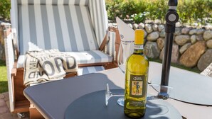 A bottle of Custoza wine on a table with a chair and a sunshade in the background. - Sylter Quartier, Whg. 1 - In Zentraler und Dennoch Ruhiger Lage Westerlands Gelegenes 2-raum (Sylt)