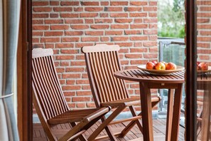 Deux chaises en bois à dossier ajouré et une table ronde en bois sur laquelle se trouve une assiette de pommes.