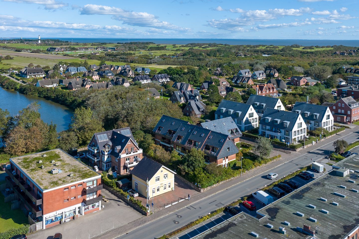 Un quartier résidentiel avec des maisons, une route et une étendue d’eau.