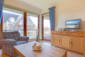 Ein gemütliches Wohnzimmer mit einer Couch, einem Couchtisch mit Kerzen, einem Fernseher und einem Holzschrank.