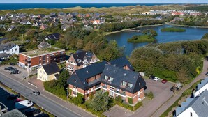 An aerial view of a residential area with houses, a road, and a lake. - Fortuna, App. 14 - Urlaub im Herzen Wenningstedts für bis zu 4 Personen (Wenningstedt-Braderup (Sylt))