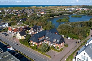 An aerial view of a residential area with houses, a road, and a lake. - Fortuna, App. 14 - Urlaub im Herzen Wenningstedts für bis zu 4 Personen (Wenningstedt-Braderup (Sylt))